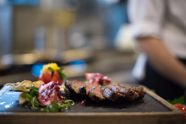 Tranches juteuses de steak grillé avec des légumes sur une planche en bois