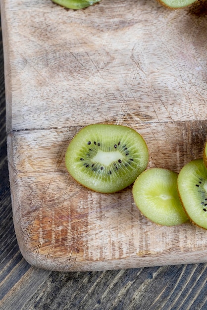 Tranches de kiwi vert mûr sur une planche à découper kiwis lavés et coupés en morceaux