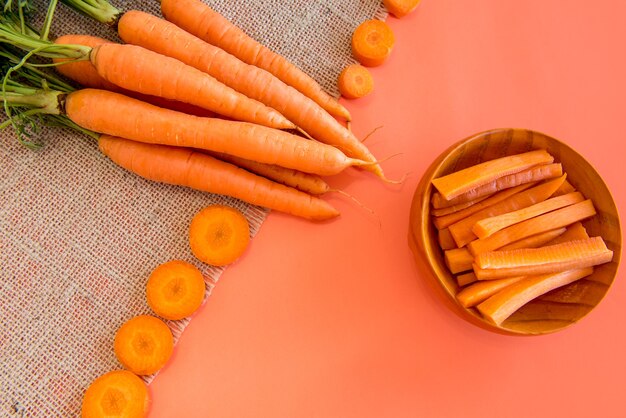 Tranches et lanières de carottes sur une table avec un fond orange.