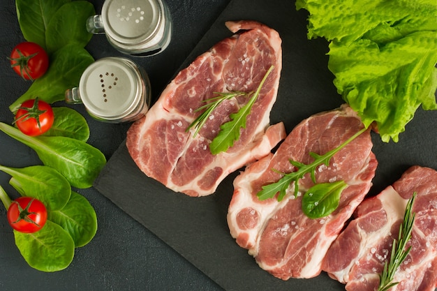 Tranches de longe de porc aux herbes, légumes et épices sur une ardoise.