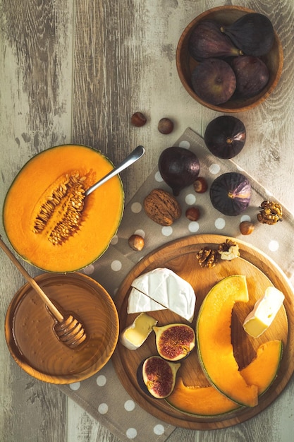 Tranches de melon cantaloup avec des feuilles de basilic camembert miel de noix de figues et de cerises séchées apéritif italien sur fond de bois