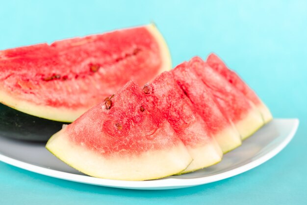 Tranches de melon d'eau sur une assiette sur fond bleu. Dessert d'été savoureux frais juteux. Stock photo