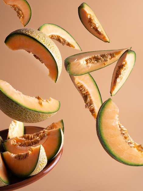 Photo tranches de melon frais tombant sur une assiette, fond clair