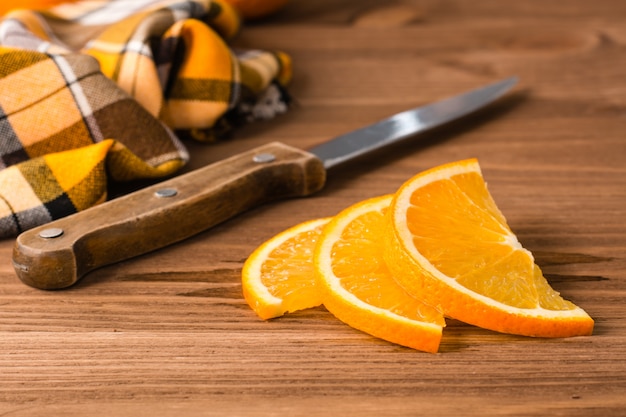 Tranches d'orange, couteau et serviette sur une table en bois