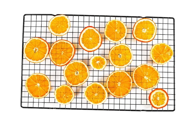 Tranches d'orange translucides fines séchées sur une grille à pâtisserie isolées sur fond blanc Vue de dessus