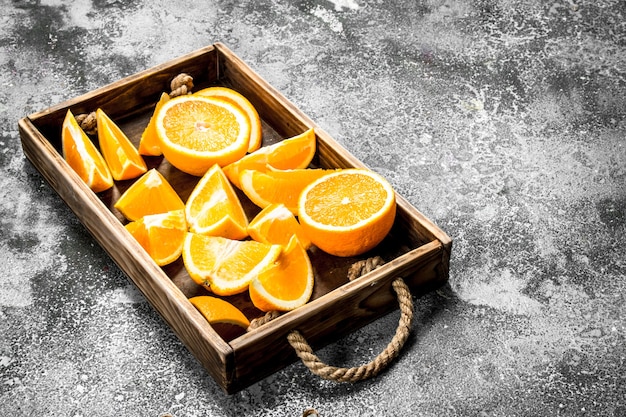 Tranches d'oranges fraîches dans un plateau en bois sur un fond rustique