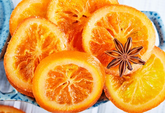 Tranches d'oranges séchées ou de mandarines à l'anis et à la cannelle dans un bol bleu. Végétarisme et alimentation saine