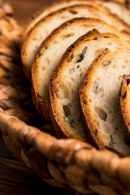 Des tranches de pain blanc tranché se trouvent dans un panier sur une table en bois grossièrement enlevées