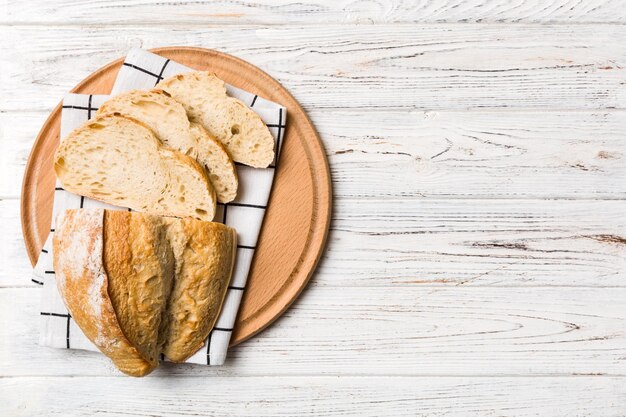 Photo tranches de pain fraîchement cuits sur une planche à découper sur la vue de dessus de fond en bois blanc