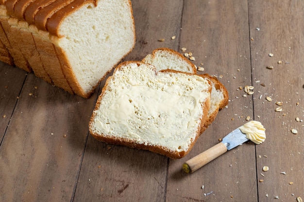 Tranches de pain miche avec de la margarine sur un bureau en bois