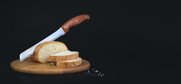 Tranches de pain de pain fraîchement cuits au four et couteau tranchant sur planche de bois rustique