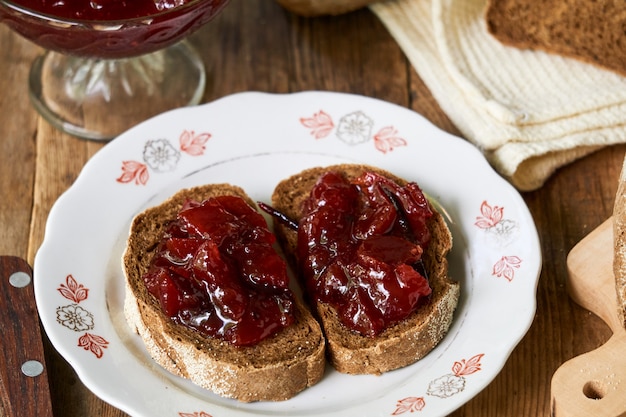 Tranches de pain de seigle avec de la confiture de prunes sur une table en bois