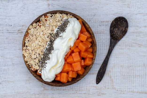 Tranches de papaye sucrée mûre avec flocons d'avoine, graines de chia et yogourt blanc