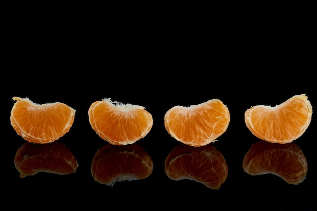 Tranches pelées de mandarine juteuse et mûre sur fond noir