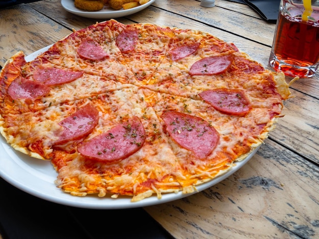 Tranches de pizza entière au salami sur une table en bois