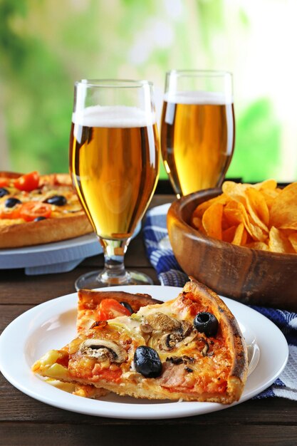 Tranches de pizza servies avec de la bière sur une table en bois