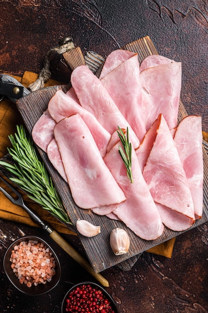 Tranches plates de jambon sandwich carré aux herbes. Fond sombre. Vue de dessus.