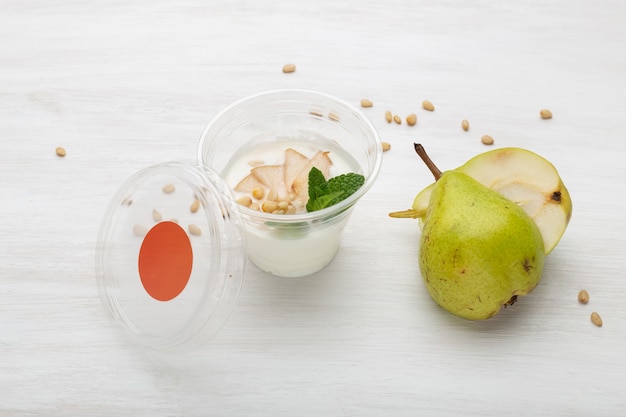 Tranches de poire yogourt et menthe et pignons de pin se trouvent dans une boîte à lunch sur un tableau blanc à côté de parsemé de