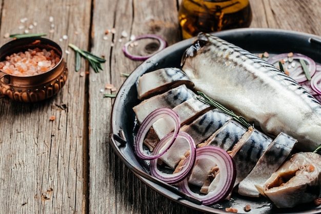 Tranches de poisson maquereau salé servi avec oignon et verdure. Concept d'alimentation, de régime ou de cuisine sains. Fond de recette de nourriture. Fermer.