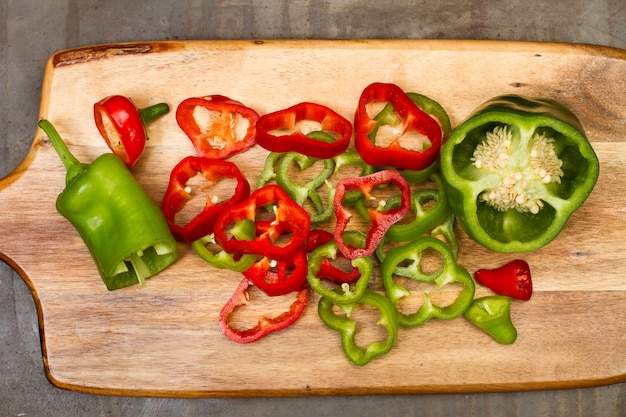 Tranches de poivrons rouges et verts sur une planche de cuisine en bois dans une vue de dessus