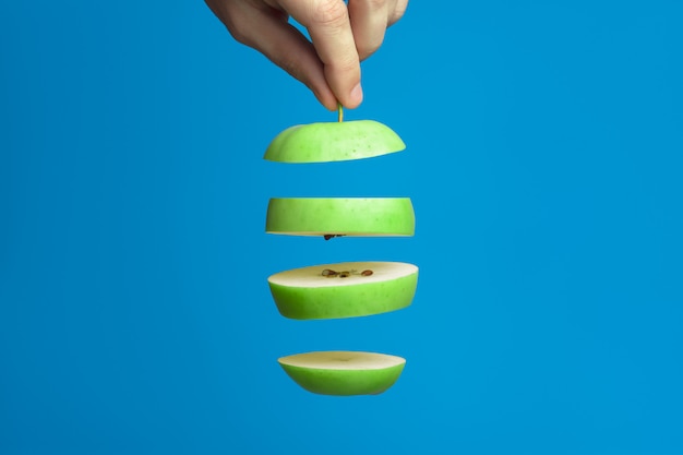 Tranches de pomme verte sur un bleu. Une des pièces de la main masculine