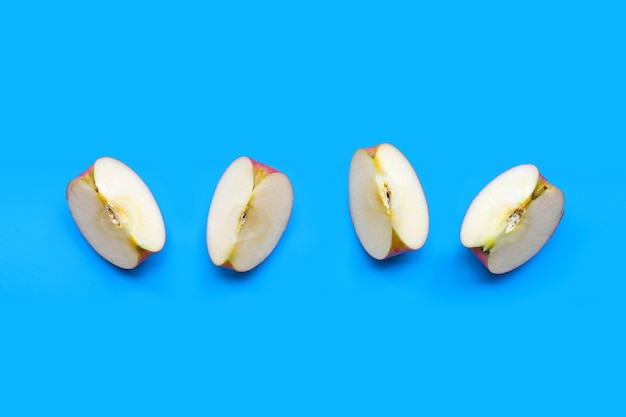 Tranches de pommes mûres sur mur bleu.