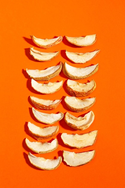 Tranches de pommes séchées ou chips de pommes à plat sur une surface orange Collation végétarienne saine Fruits secs