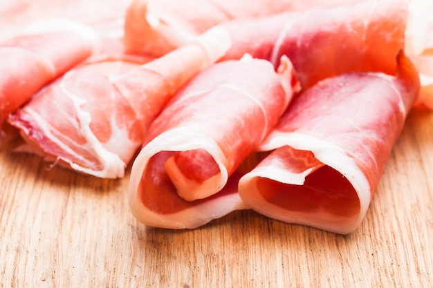 Tranches de prosciutto se bouchent sur la table en bois