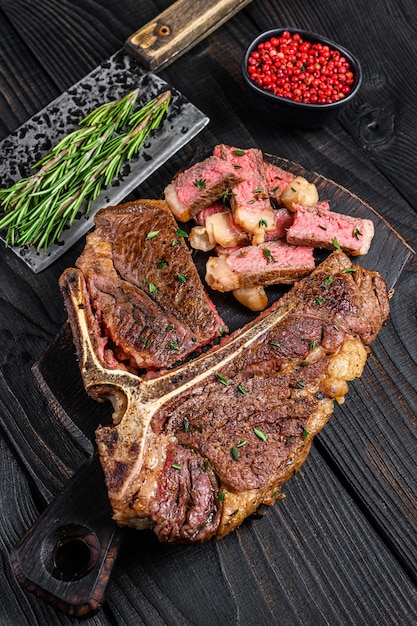 Tranches et rôti T-bone ou bifteck de viande de bœuf porterhouse pour menu steakhouse sur table en bois. Vue de dessus.