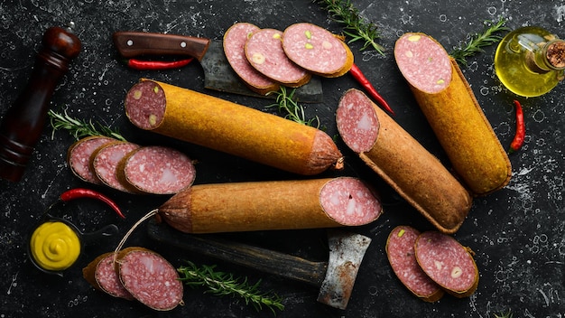 Tranches de salami au romarin et épices sur fond de pierre noire Vue de dessus Style rustique