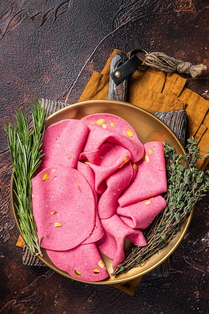 Tranches de salami aux pistaches en plaque d'acier avec thym et romarin Fond sombre Vue de dessus