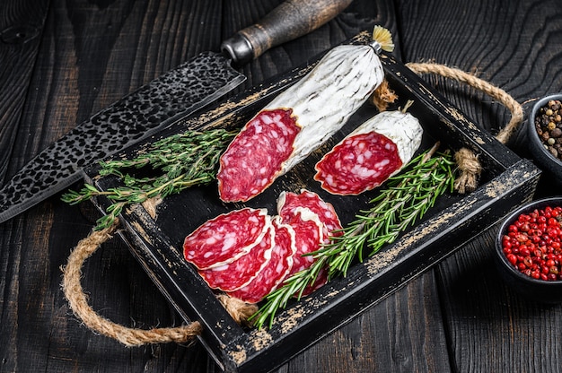 Tranches de salami salchichon séché à sec dans un plateau en bois.