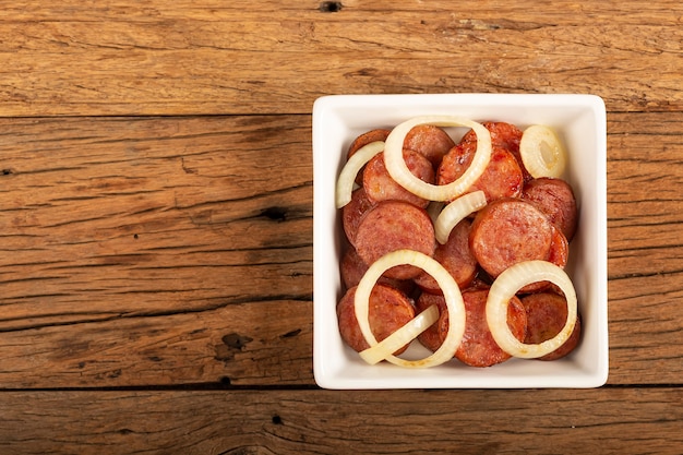 Tranches de saucisse calabraise à l'oignon sur fond de bois