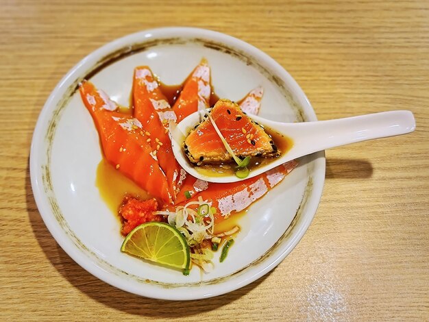 Tranches de saumon cru avec sauce ponzu aigre dans un petit plat