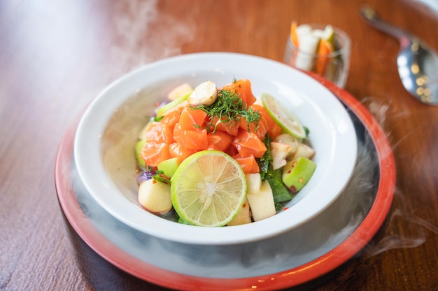 Tranches de saumon épicé avec salade de fruits dans un bol en céramique blanche