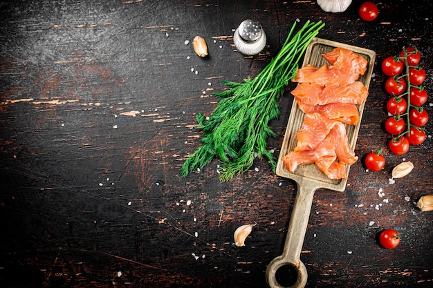 Tranches de saumon salé sur une planche à découper avec aneth et tomates