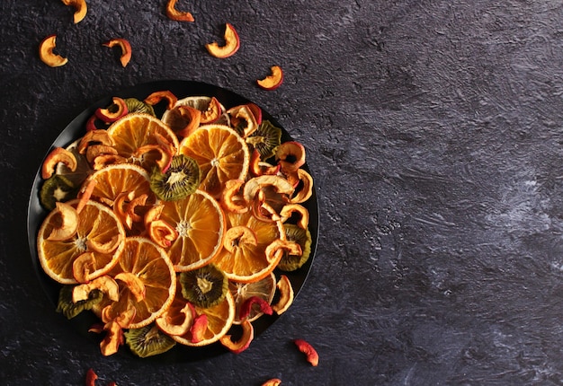 Tranches séchées de pommes kiwi citron orange sur fond sombre