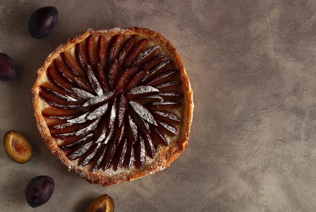 Tranches de tarte aux prunes avec du sucre en poudre sur fond gris