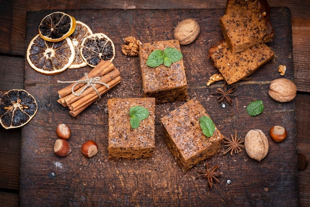 Tranches de tarte carrées cuites au four avec des noix sur une planche de bois blanche, un gâteau éponge