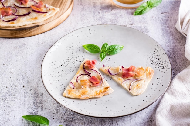 Tranches de tarte flammkuchen française avec bacon, fromage à la crème et oignons sur une assiette