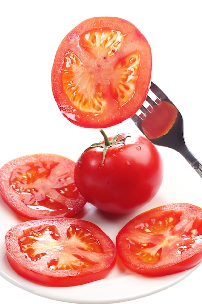 Photo tranches de tomate sur une fourchette et sur une assiette isolated on white