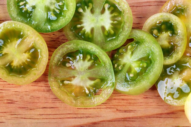 Tranches de tomate verte sur fond de bois