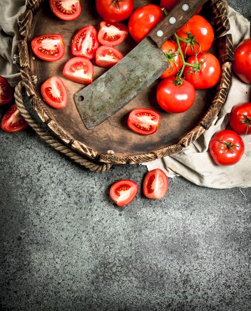 Tranches de tomates fraîches sur le plateau avec un vieux couteau sur fond rustique