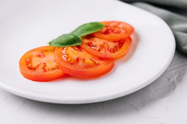 Tranches de tomates rouges et feuilles de basilic