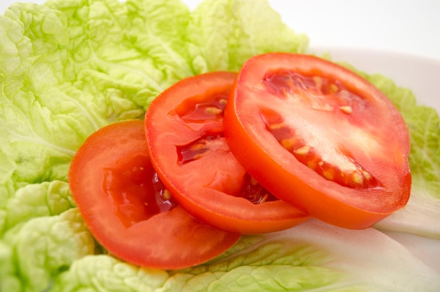 Tranches de tomates rouges sur des feuilles de laitue.