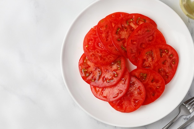 Des tranches de tomates sont empilées sur une assiette blanche dans un cercle Vue de dessus espace de copie maquette Salade vide