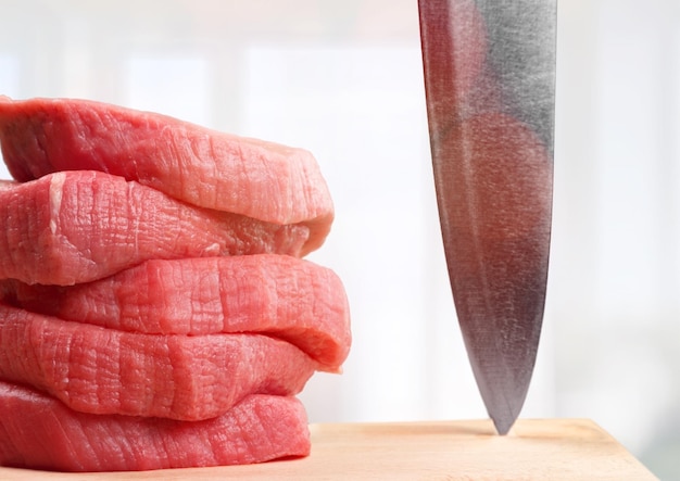 tranches de viande crue et couteau sur la planche à couper