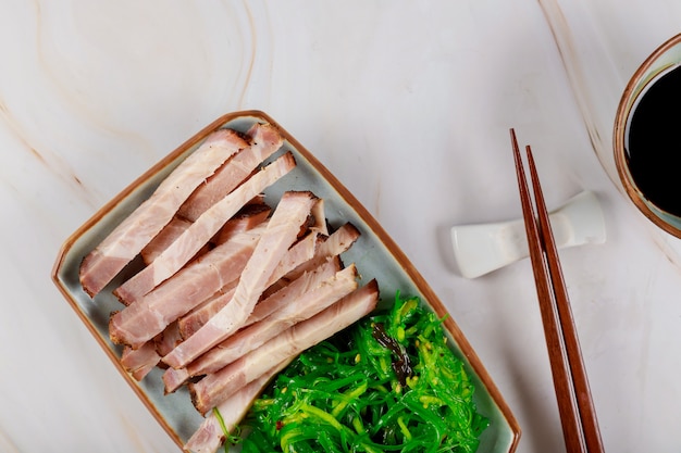 Tranches de viande à la japonaise avec algues, sauce et baguettes