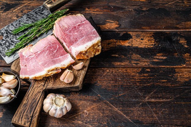 Tranches de viande de porc fumé gammon sur une planche à découper rustique en bois.