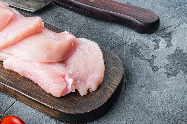Tranches de viande de poulet non cuites, sur fond gris